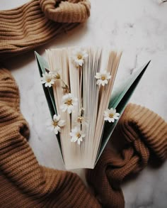 an open book sitting on top of a table next to some gloves and flowers in it