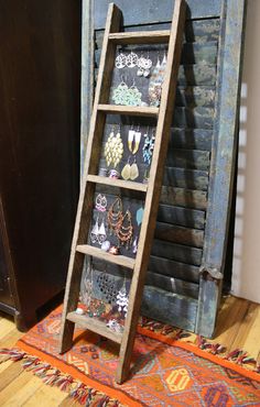 an old wooden ladder stands in front of a door with earrings on it and a rug