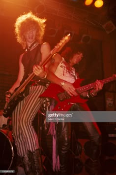 two people on stage with guitars and one person in striped pants holding an electric guitar