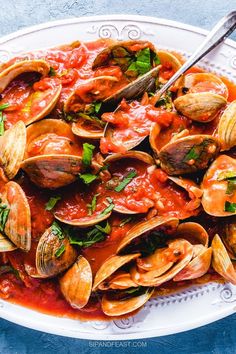 a white plate filled with clams and sauce on top of a blue tablecloth