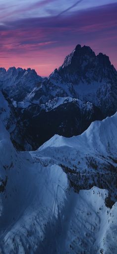 the mountains are covered in snow as the sun sets