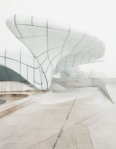 an artistic view of a building with curved roof and water feature in the foreground