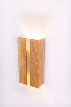 a wooden object with a light on it's side against a white wall in the shape of a rectangle