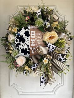 a wreath on the front door decorated with flowers and an i love my cow print