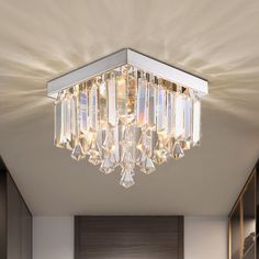 a crystal chandelier hanging from the ceiling in a room with white walls and cabinets