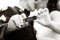 a man and woman kissing while holding up a small card that says becell