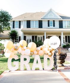 a large sign that says grad in front of a big house with balloons on it