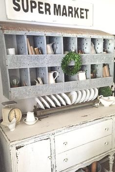 an old dresser with plates and cups on it in a room that has a super market sign above it