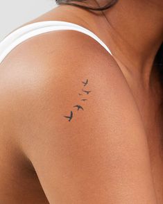 a woman with a tattoo on her shoulder has birds flying above her arm and behind her head