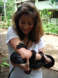 a woman holding a baby monkey in her arms