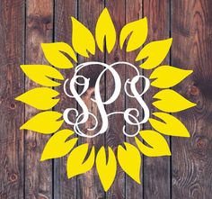 the monogrammed sunflower is shown in white and yellow on a wooden background