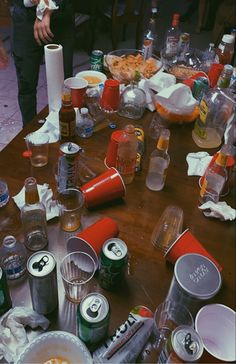 the table is covered with many empty cups and food items, including sodas, donuts, and pizza