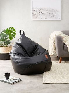 a bean bag chair sitting on top of a floor next to a rug and potted plant