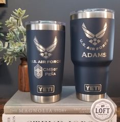 two navy blue yeti tumblers sitting on top of a stack of books