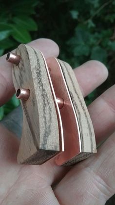 a person holding a wooden ring in their hand with copper rings on it's sides