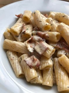 a white plate topped with pasta and bacon