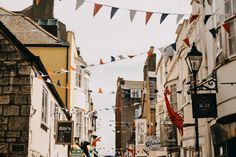 people are walking down the street in an old european town with bunting and flags