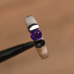 It is a natural amethyst ring. The main stone is 5 mm*5 mm round cut.weight about 0.48 carats.The basic metal is sterling silver and plated with rhodium.To change the metal to a solid gold (white/rose) or platinum is also available, please ask for a quotation if you want.You can also go to my shop Home for more elegant rings: https://www.etsy.com/shop/godjewelry?ref=hdr_shop_menu Amethyst is February birthstoneMore amethyst rings:https://www.etsy.com/shop/godjewelry?ref=seller-platform-mcnav&sec White Gold Amethyst Ring Round Cut, White Gold Amethyst Ring With Round Cut, Classic Amethyst Round Cut Birthstone Ring, Classic Amethyst Birthstone Ring With Round Cut, Minimalist Amethyst Birthstone Ring For Anniversary, Purple Round Birthstone Ring, Purple Solitaire Birthstone Ring, Purple Birthstone Ring With Round Cut, Modern Round Birthstone Ring