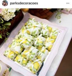 there is a tray full of yellow and white desserts on the table next to flowers