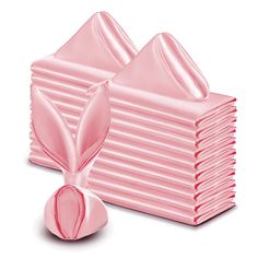 a stack of pink tissue sitting on top of a pile of folded napkins next to each other