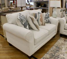 a living room filled with white furniture and lots of pillows on top of it's back