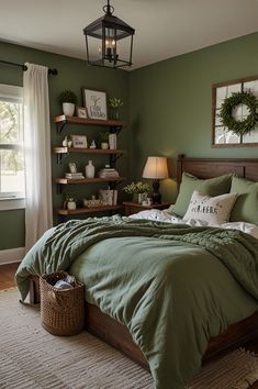 a bed with green comforter and pillows in a bedroom next to a lamp on the wall