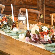 the table is set with candles, flowers and greenery for an autumn centerpiece