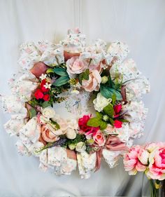 a wreath with flowers on it sitting next to two vases filled with flowers and greenery