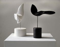 two sculptures sitting on top of a white table in front of a wall with the words sofordis above it