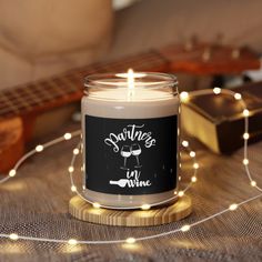 a lit candle sitting on top of a table next to a guitar and string lights