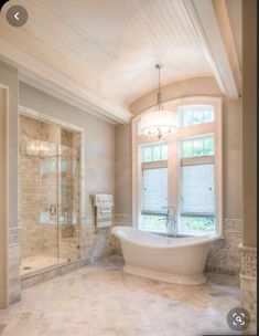 a large bathroom with an oval tub and two windows in the ceiling, along with marble tile flooring