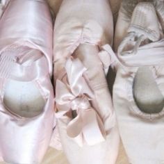 three pairs of pink ballet shoes with bows on them