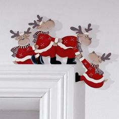 three christmas reindeers are standing on top of a white door frame with their arms in the air