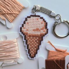 a cross stitch keychain is shown with thread and spools on the table