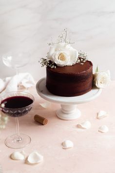 a chocolate cake sitting on top of a table next to a glass of wine