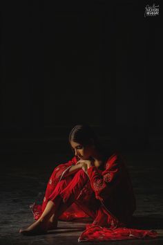 a woman in a red dress sitting on the ground