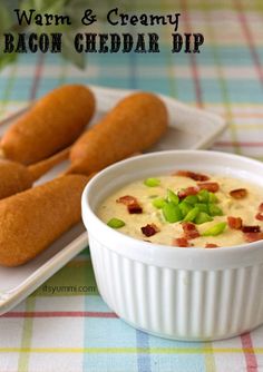 bacon cheddar dip in a white bowl next to two hot dogs on a plate