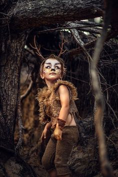 a young boy dressed up as a creature in the woods