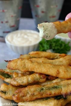 a person is dipping something into some fried food on a plate with other dishes in the background