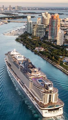 an aerial view of a cruise ship in the water near a large city with tall buildings