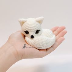 a hand holding a small white crocheted stuffed animal in it's palm