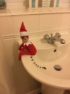 an elf is sitting on the edge of a sink