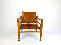 a brown leather chair sitting on top of a white floor next to a wooden frame