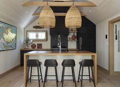 a kitchen with three stools and a bar in the middle, next to an open floor plan