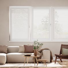 a living room filled with furniture and windows covered in white plantation blinds on top of them