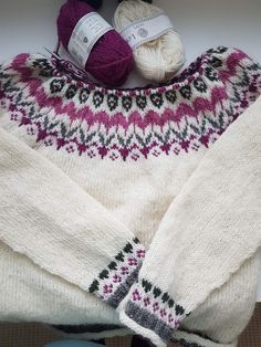 a sweater and balls of yarn sitting on top of a white table next to each other