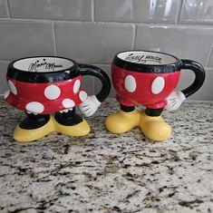 two mickey mouse mugs sitting on top of a counter