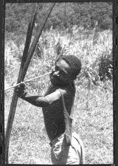 an old photo of a man holding a bow and arrow