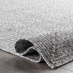 the grey and white rug is laying on top of wood flooring, with an open end