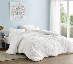 a white comforter on a bed in a room with blue walls and wooden floors